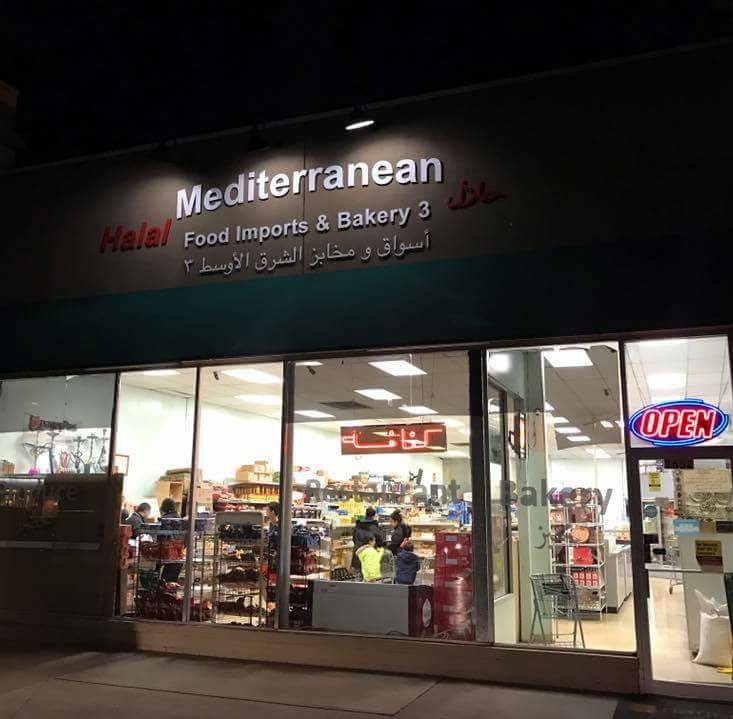 Nighttime view of Halal-Mediterranean Food #3 storefront, with people visible inside through the glass door